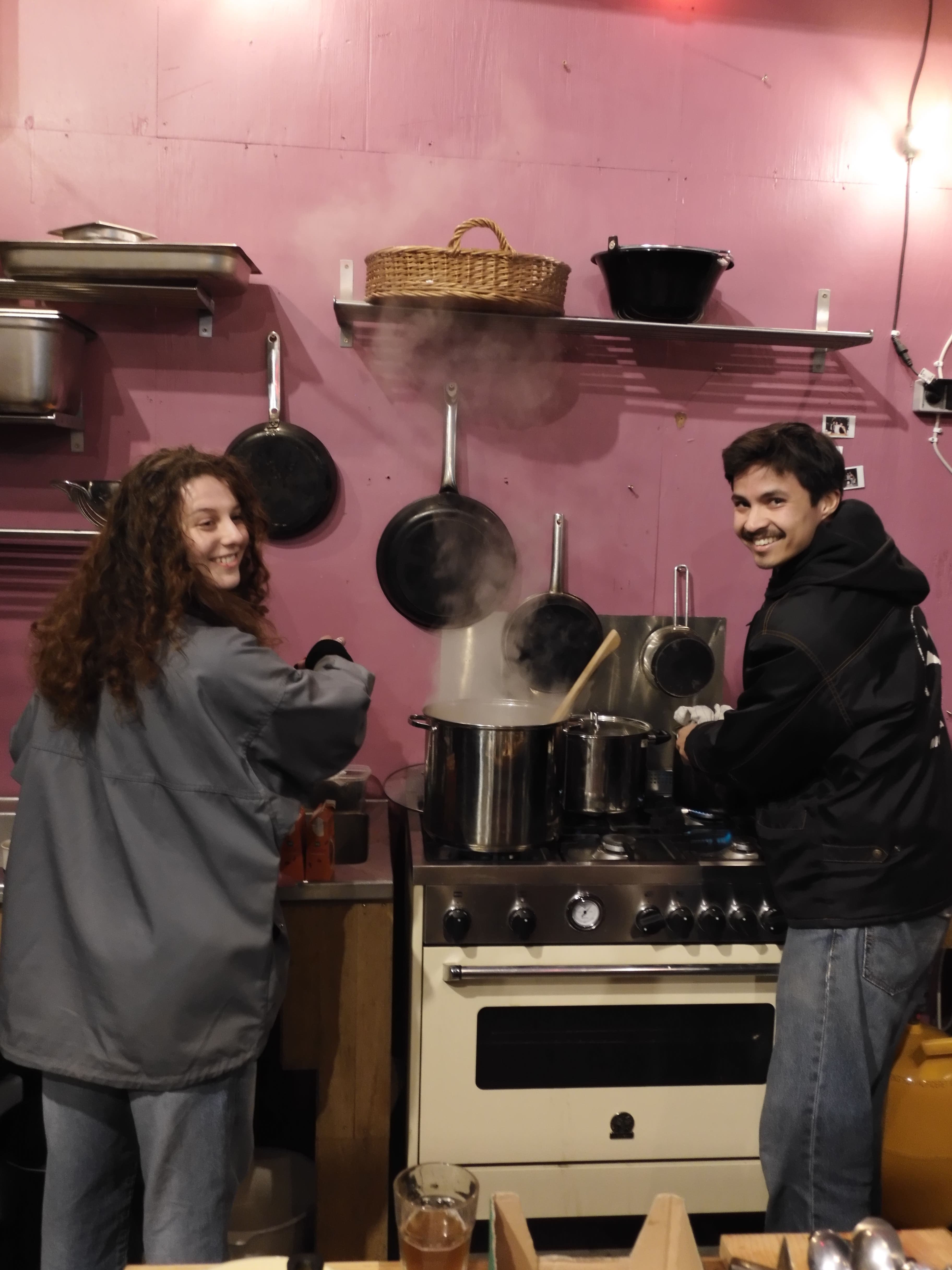 Two attendees looking happy cooking lunch on the kitchen stove.