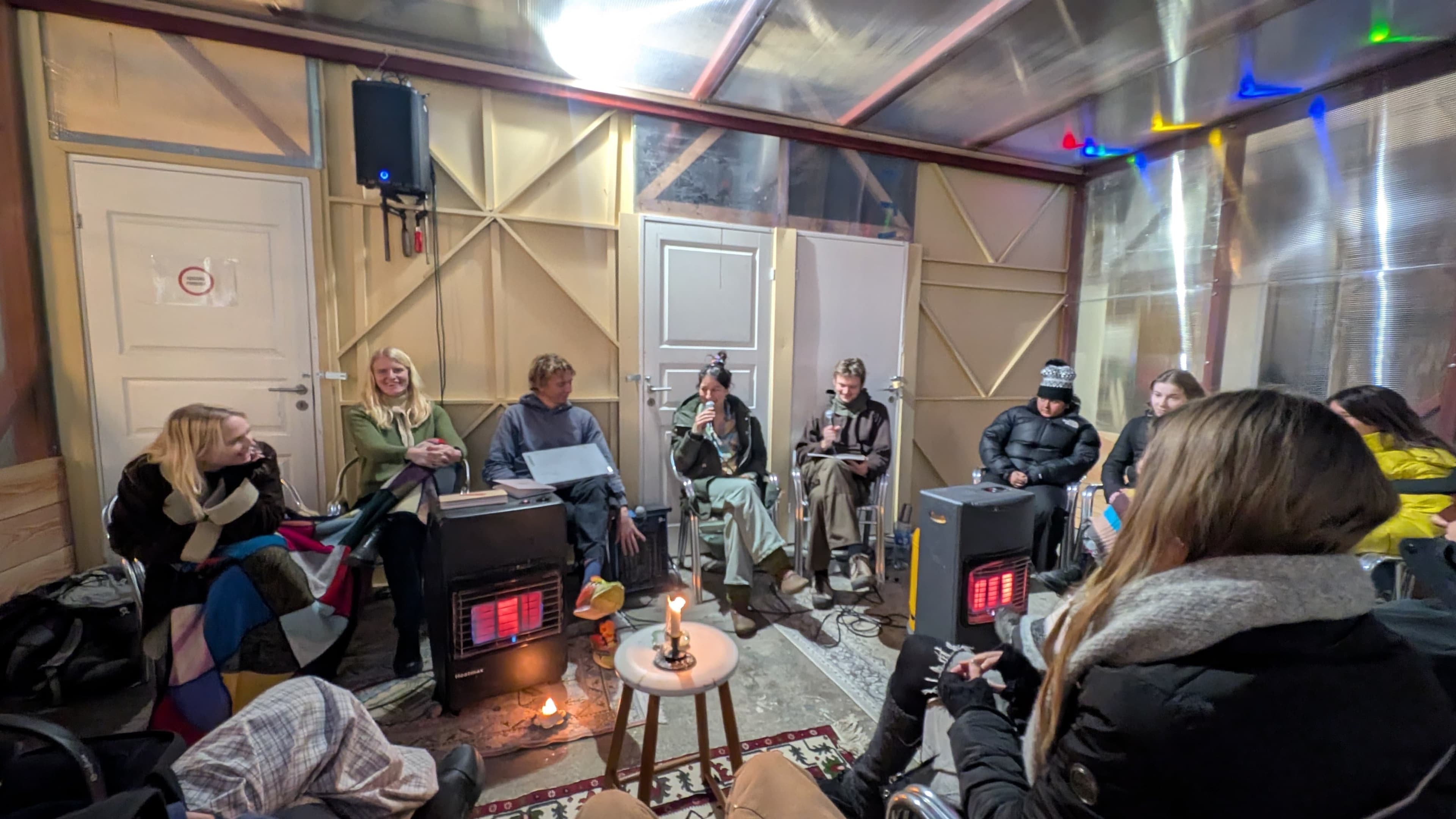 Attendees wrapped in blankets, having class in the common room.